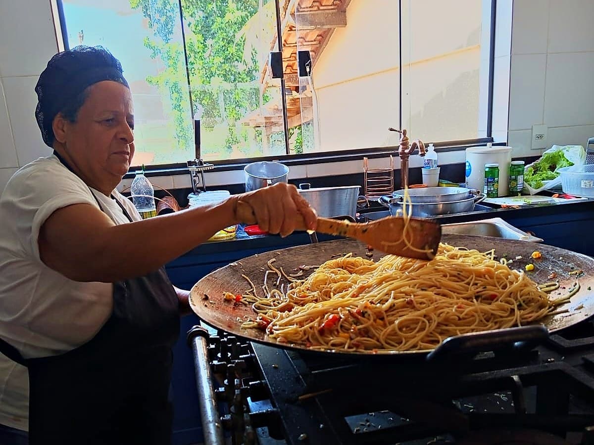 Cozinheira preparando macarrão em panela grande