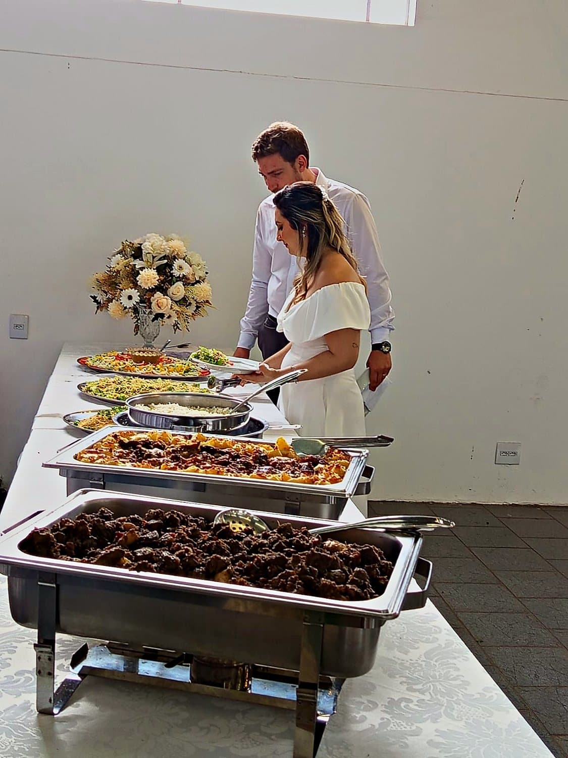 Os noivos servindo-se no buffet do próprio casamento