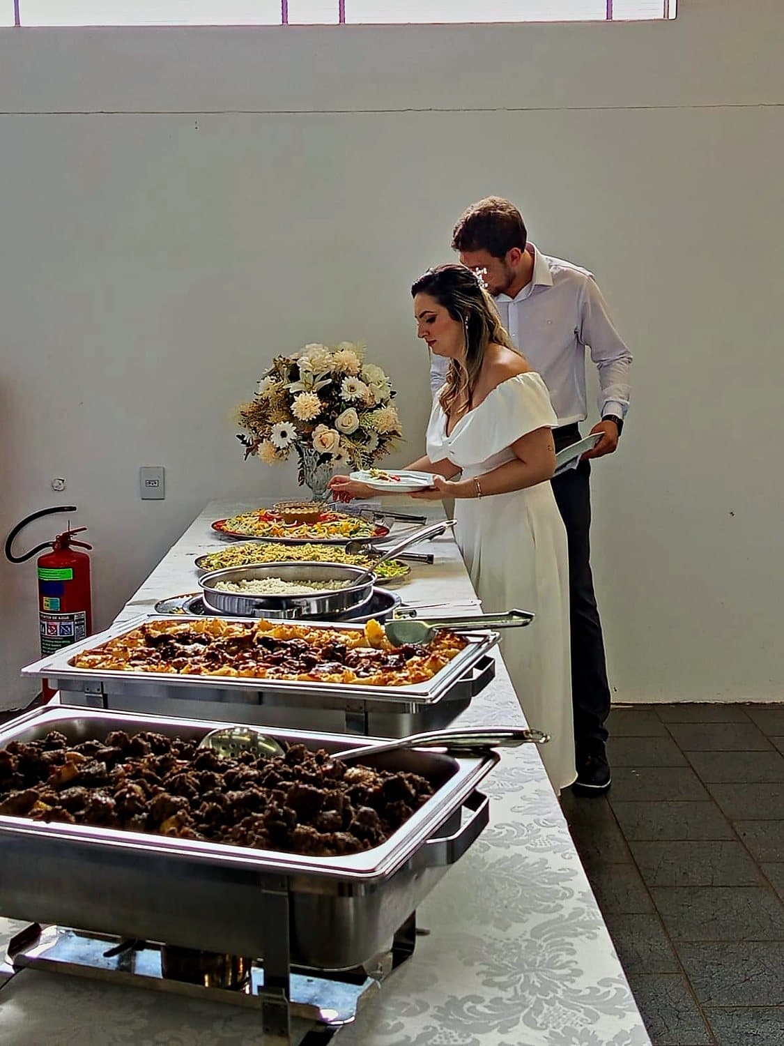 Noivos escolhendo os pratos na mesa de buffet do casamento