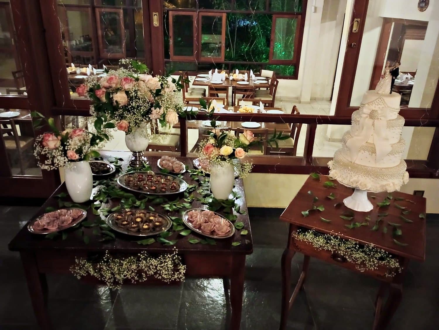 Mesa de doces do casamento com bolo de andares e arranjos de flores