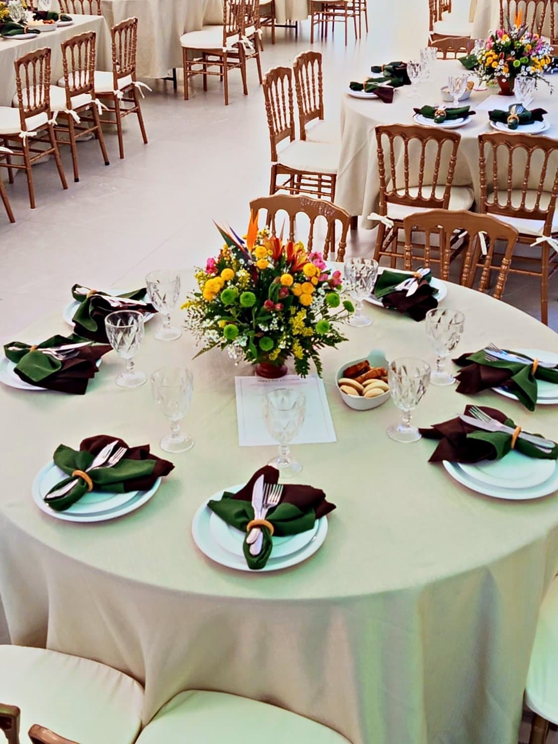 Mesa redonda posta com louça, taças e arranjo de flores