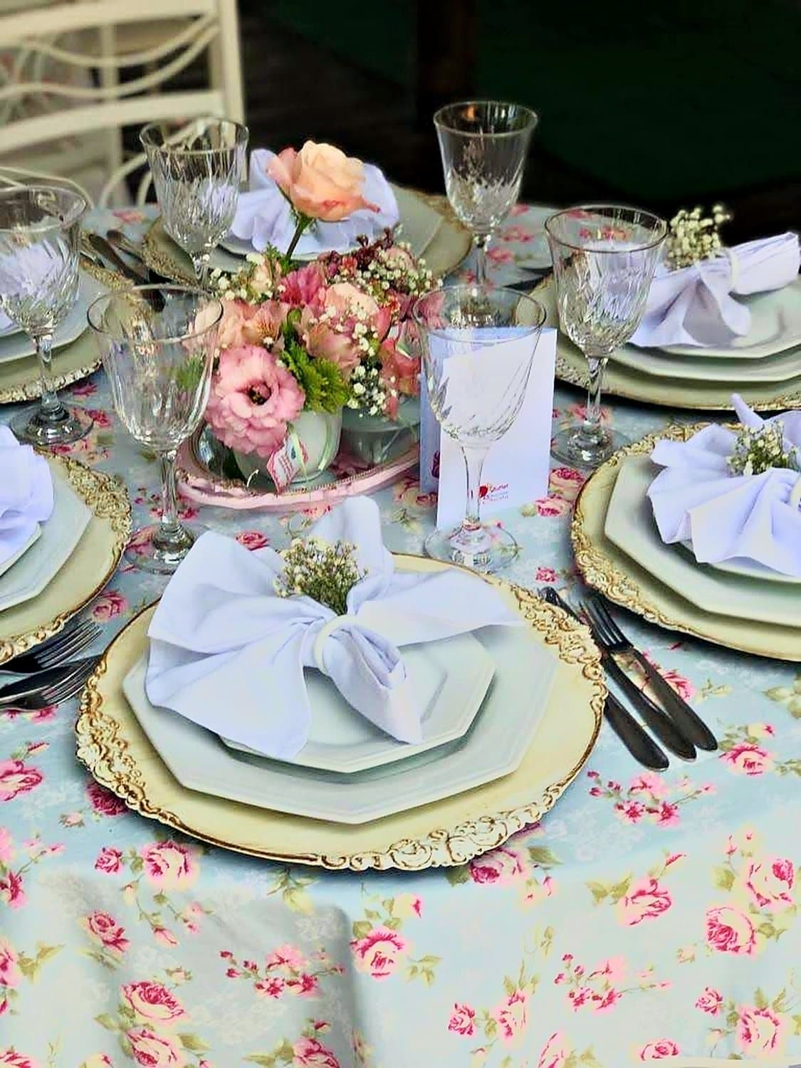 Lugar à mesa com louça, guardanapo e arranjo delicado de flores