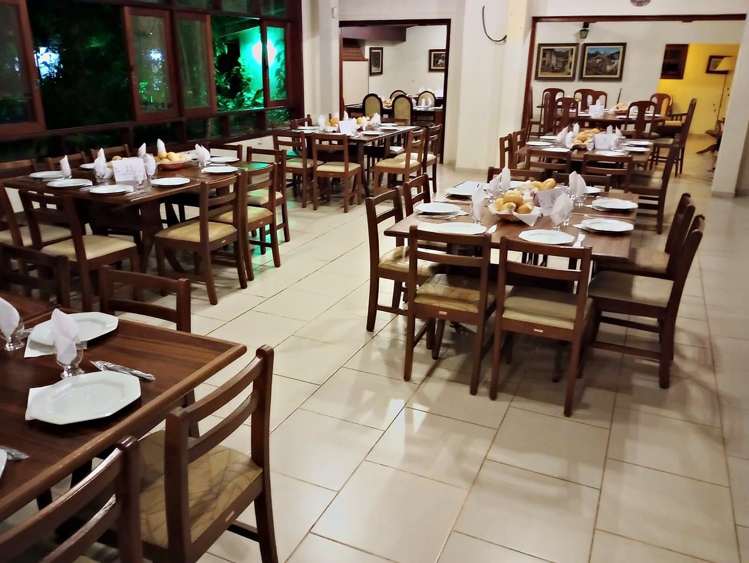 Salão de jantar com mesas postas e iluminação noturna
