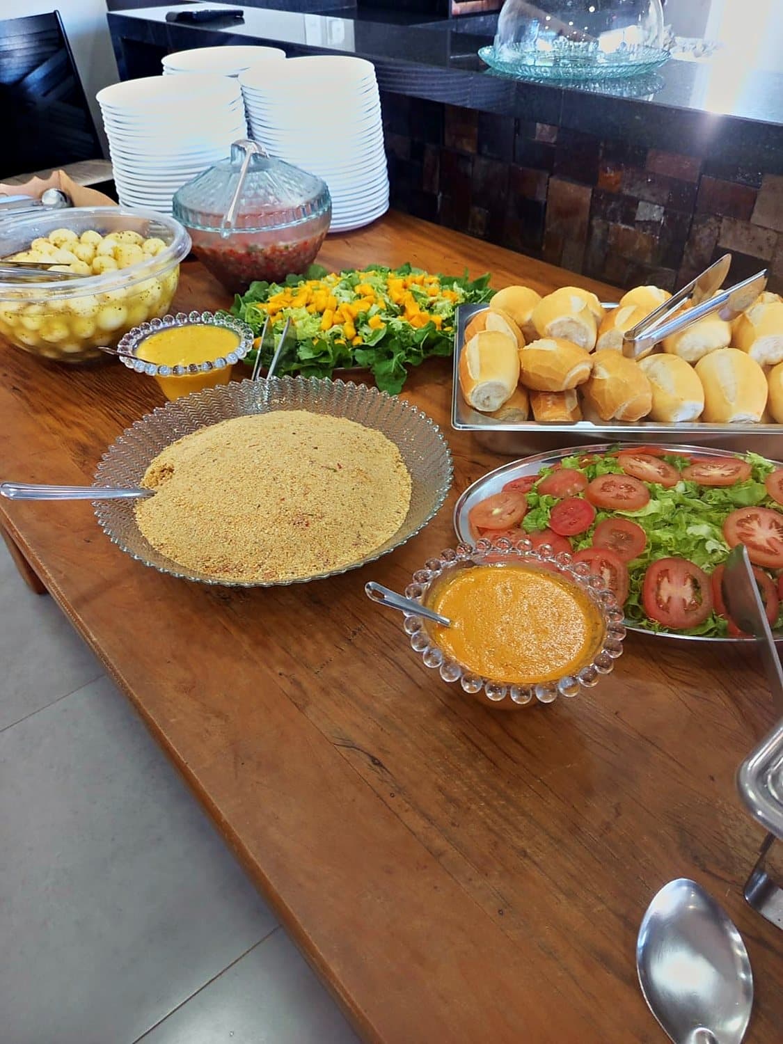 Mesa de buffet com pães, saladas e farofa