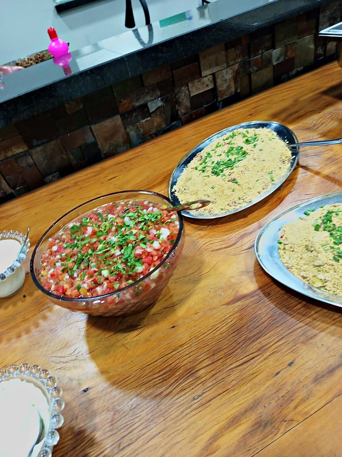 Saladas e acompanhamentos servidos em mesa de madeira