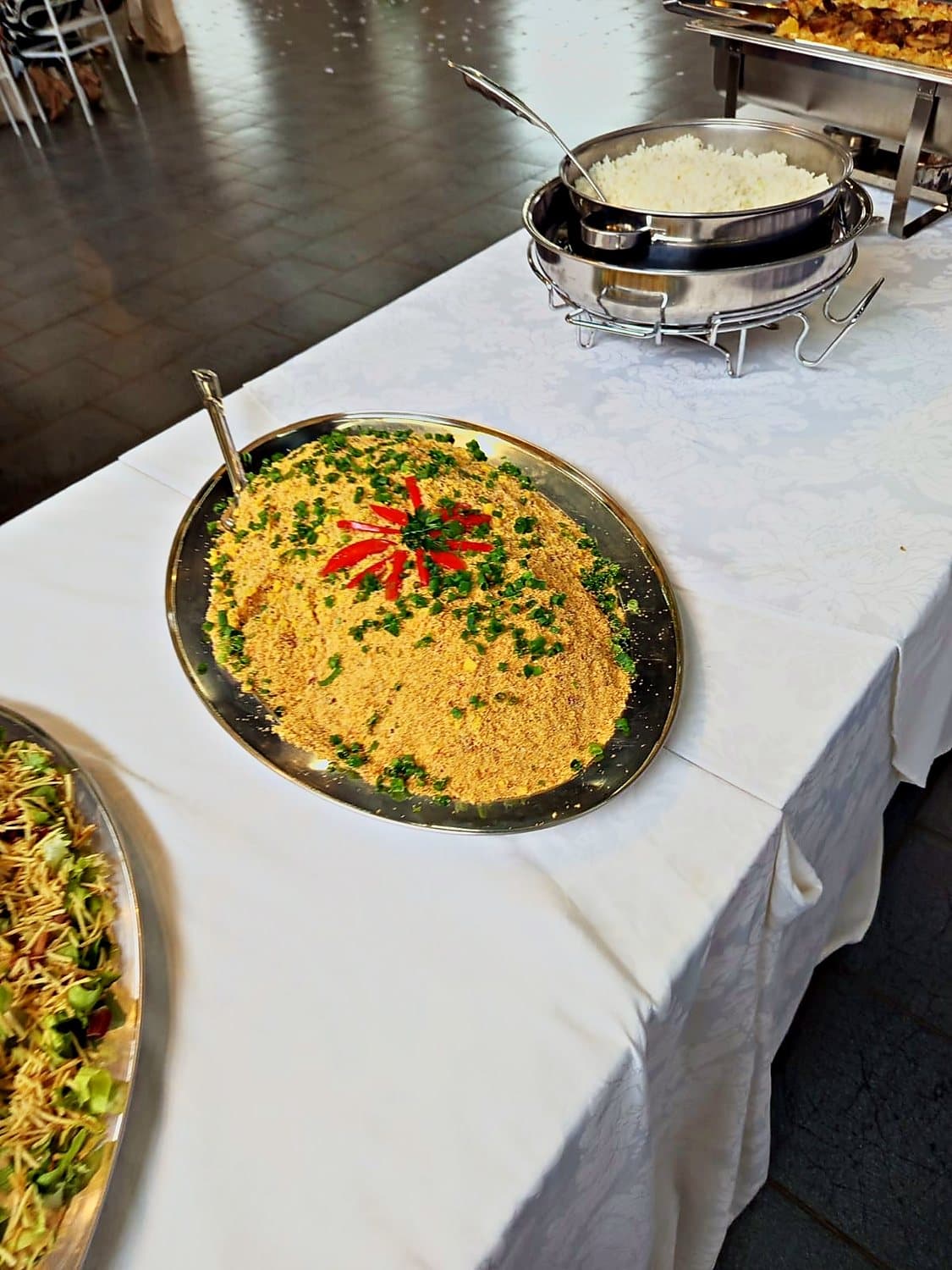 Mesa de buffet com toalha branca e travessas de arroz