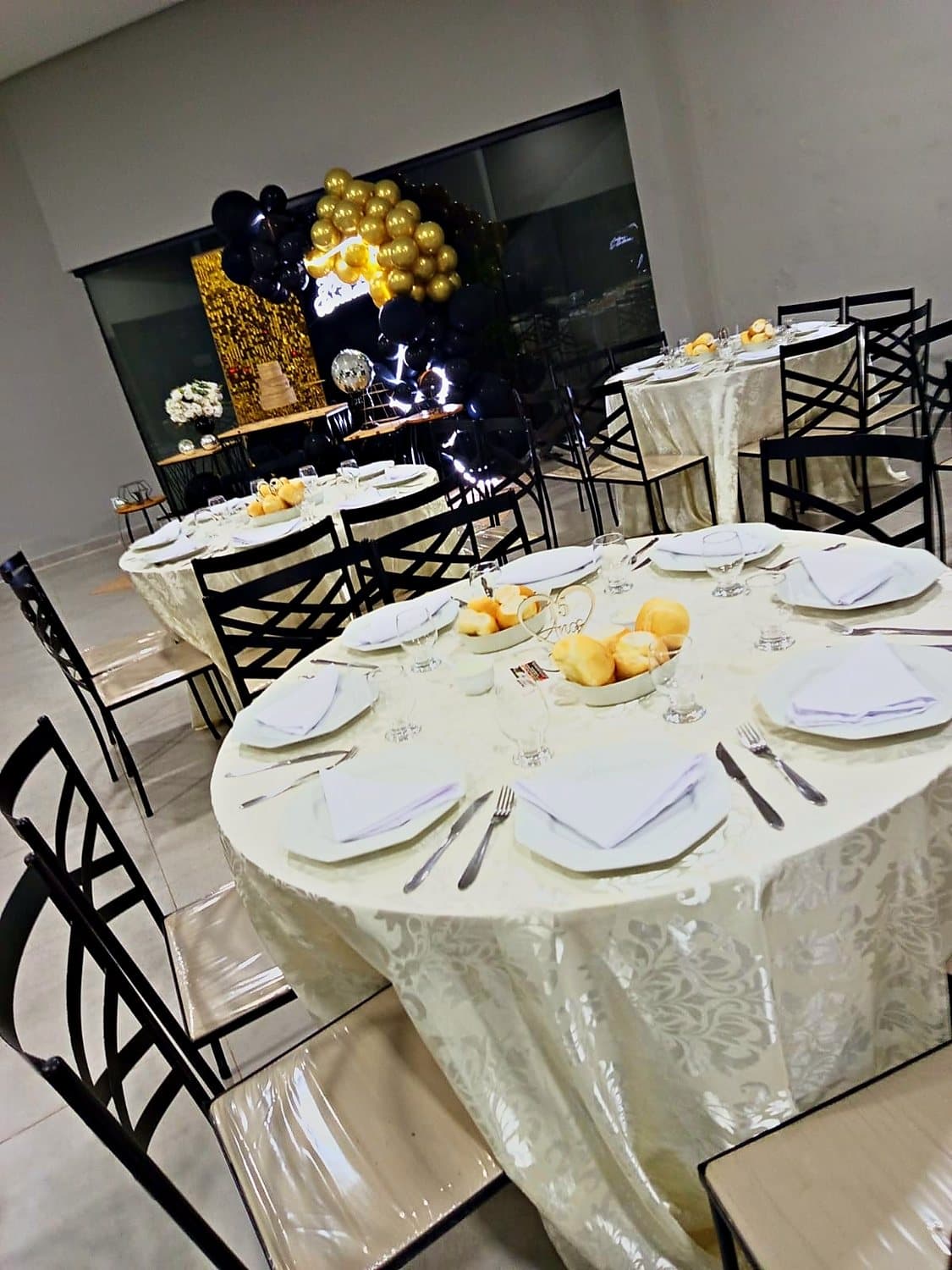 Mesa posta para aniversário, com balões dourados ao fundo