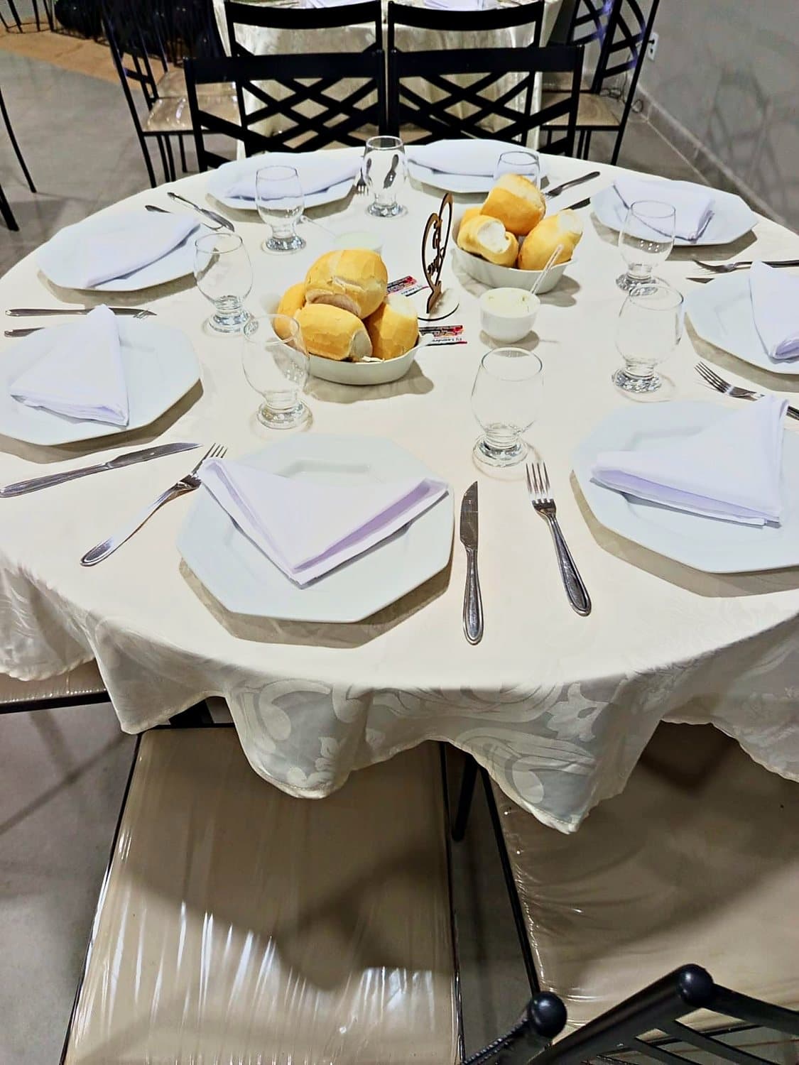 Lugar à mesa com louça, taças e guardanapo dobrado