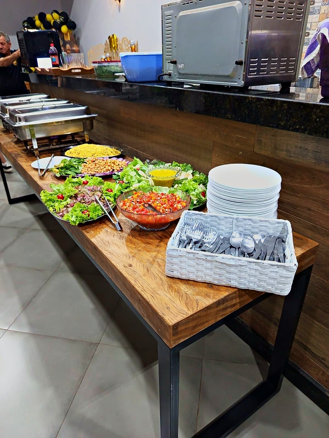 Mesa de saladas e acompanhamentos com pratos empilhados